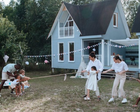Happy family playing tug of war in front of cozy houses during a summer day.
